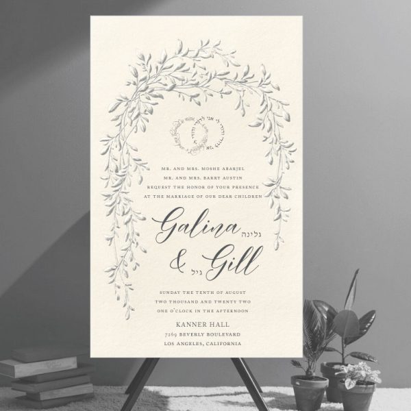 This is not a flat, digitally printed invitation—it's an embossed design that brings true dimension and artistry to the piece. The raised embossing adds depth and texture to a graceful sketch of trailing vines, arching over the text in the symbolic shape of a chuppah. Aptly named the Arched Foliage Chuppah Jewish Wedding Invitation, it captures tradition and elegance in every detail. At the top, the Hebrew phrase Ani L’dodi V’dodi Li (I am my beloved’s and my beloved is mine) appears in the shape of intertwined wedding rings, emphasizing unity and love. The wedding details are arranged in a refined layout, featuring elegant script fonts alongside the Hebrew names of the couple.