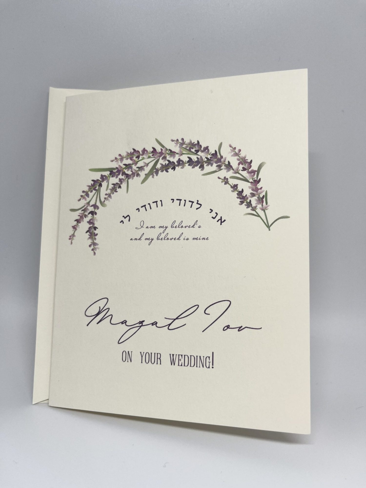 Celebrate love with our stunning Purple Flower Jewish wedding greeting card pack. The front features a beautiful purple flower shaped like a Chuppah, adorned with the phrase "Ani le'dodi vedodi li" in both Hebrew and English, along with the elegant message "Mazal Tov on your wedding day." The inside is blank, allowing you to personalize your message for the happy couple, perfect for sharing heartfelt wishes on their special day!