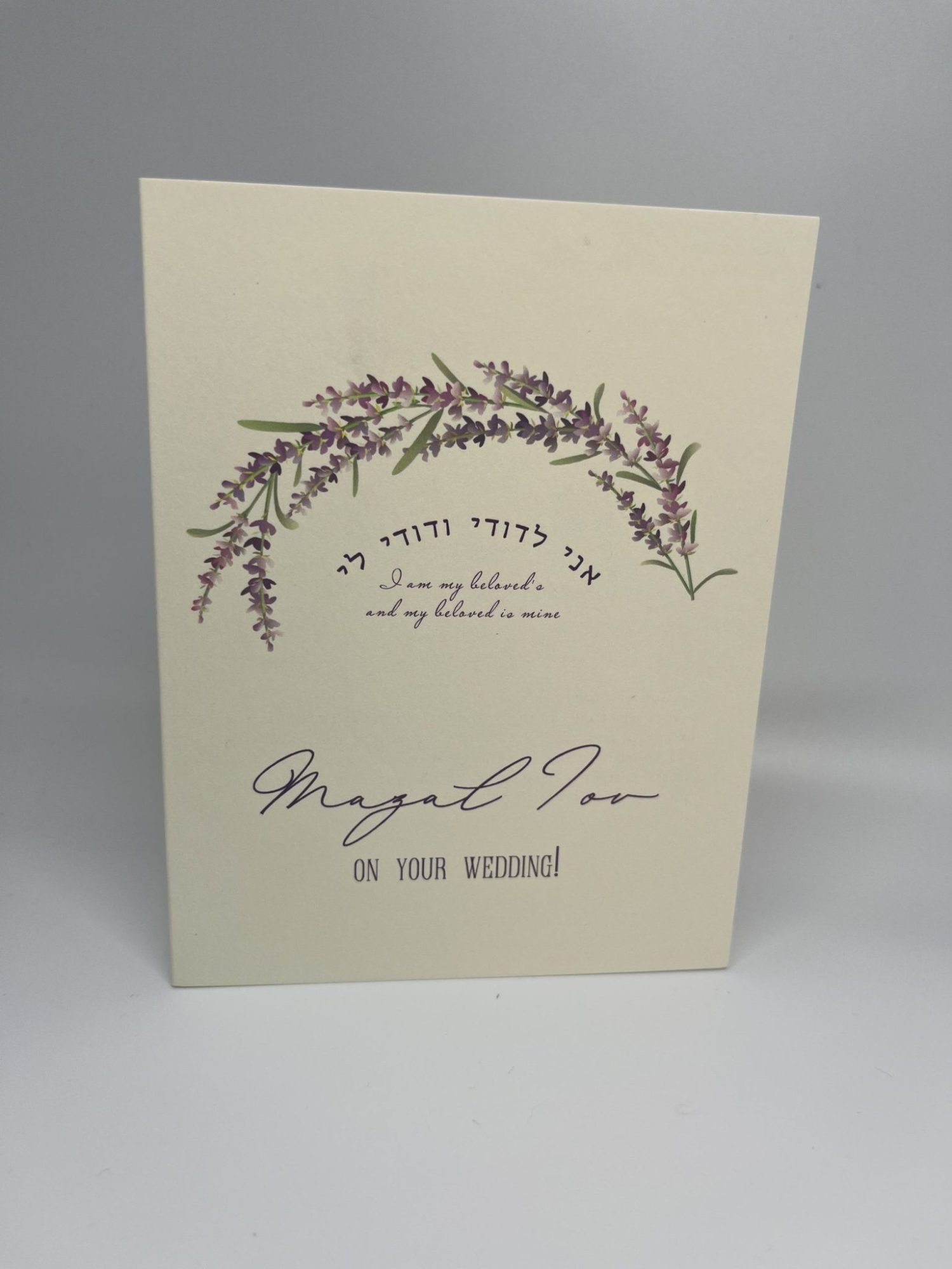 Celebrate love with our stunning Purple Flower Jewish wedding greeting card pack. The front features a beautiful purple flower shaped like a Chuppah, adorned with the phrase "Ani le'dodi vedodi li" in both Hebrew and English, along with the elegant message "Mazal Tov on your wedding day." The inside is blank, allowing you to personalize your message for the happy couple, perfect for sharing heartfelt wishes on their special day!