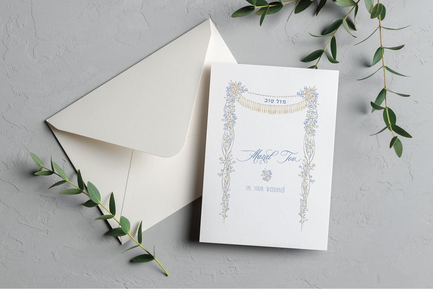 Garden of Eden Chuppah Wedding Card | Gold Foil Mazal Tov Celebrate a beautiful union with our Garden of Eden Chuppah Wedding Card. This elegant design features a delicate floral trellis and an illustrative chuppah canopy. For a touch of sophistication, key details of the chuppah are printed in shimmering gold foil. The card includes Mazal Tov in both Hebrew and English script, making it the perfect choice for sending your warmest wishes to the happy couple. Each card is printed on our signature 130lb. premium heavy ecru cardstock using professional presses for a high-end, tactile feel. The inside is left completely blank, providing plenty of space for your heartfelt personal message.