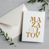 This Gold Foil Mazal Tov Greeting Card is a stunning way to celebrate weddings, Bar or Bat Mitzvahs, and new beginnings. Featuring a bold, modern typographic design with Mazal Tov in both English and Hebrew, the shimmering gold foil adds a touch of elegance to any occasion. Each card is printed on our signature 130lb. premium heavy ecru cardstock using professional presses for a high-end, tactile feel. The inside is left blank for your own personal message.