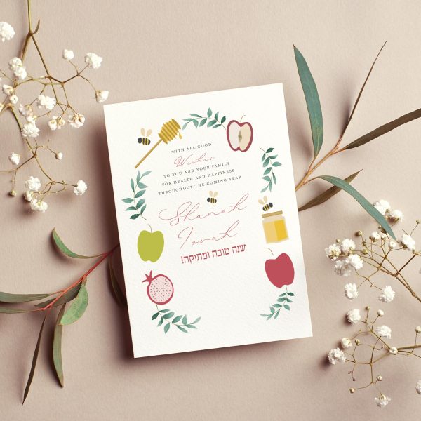 Rosh Hashanah greeting card with watercolor wreath of apples, honey jar, pomegranate and bees, Hebrew text שנה טובה ומתוקה, Shanah Tovah script lettering, cream background