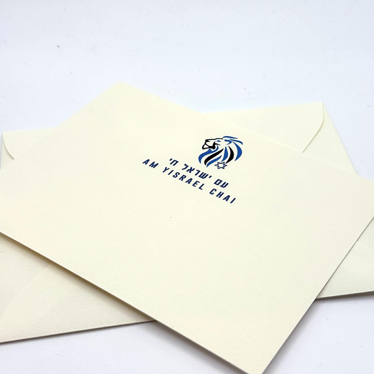Cream-colored invitation card with navy blue lion head and Star of David logo, featuring Hebrew text and "AM YISRAEL CHAI" in English and Hebrew.